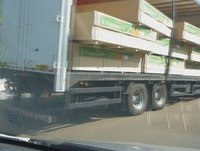 Caminhão Sider com MDF caindo a carga.